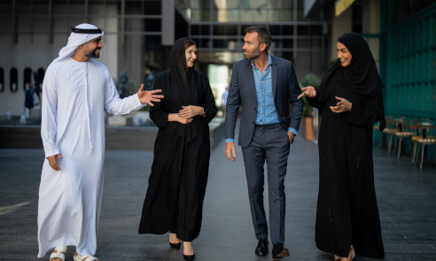 Four business people from different cultures and backgrounds walk and talk while having fun.