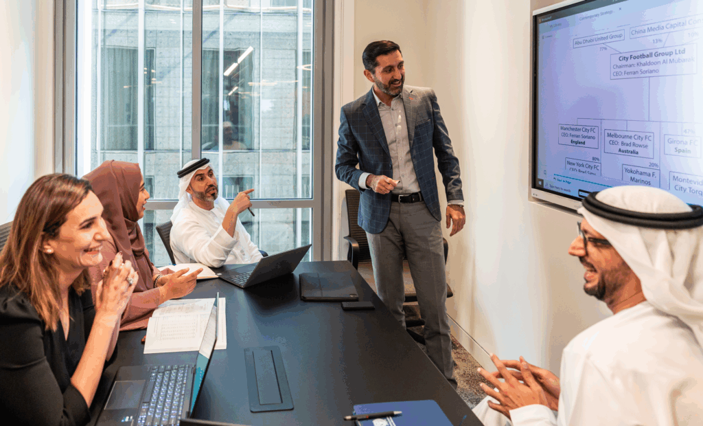 Georgetown students and business people from different background discuss a chart on a monitor. The chart isn't in focus.