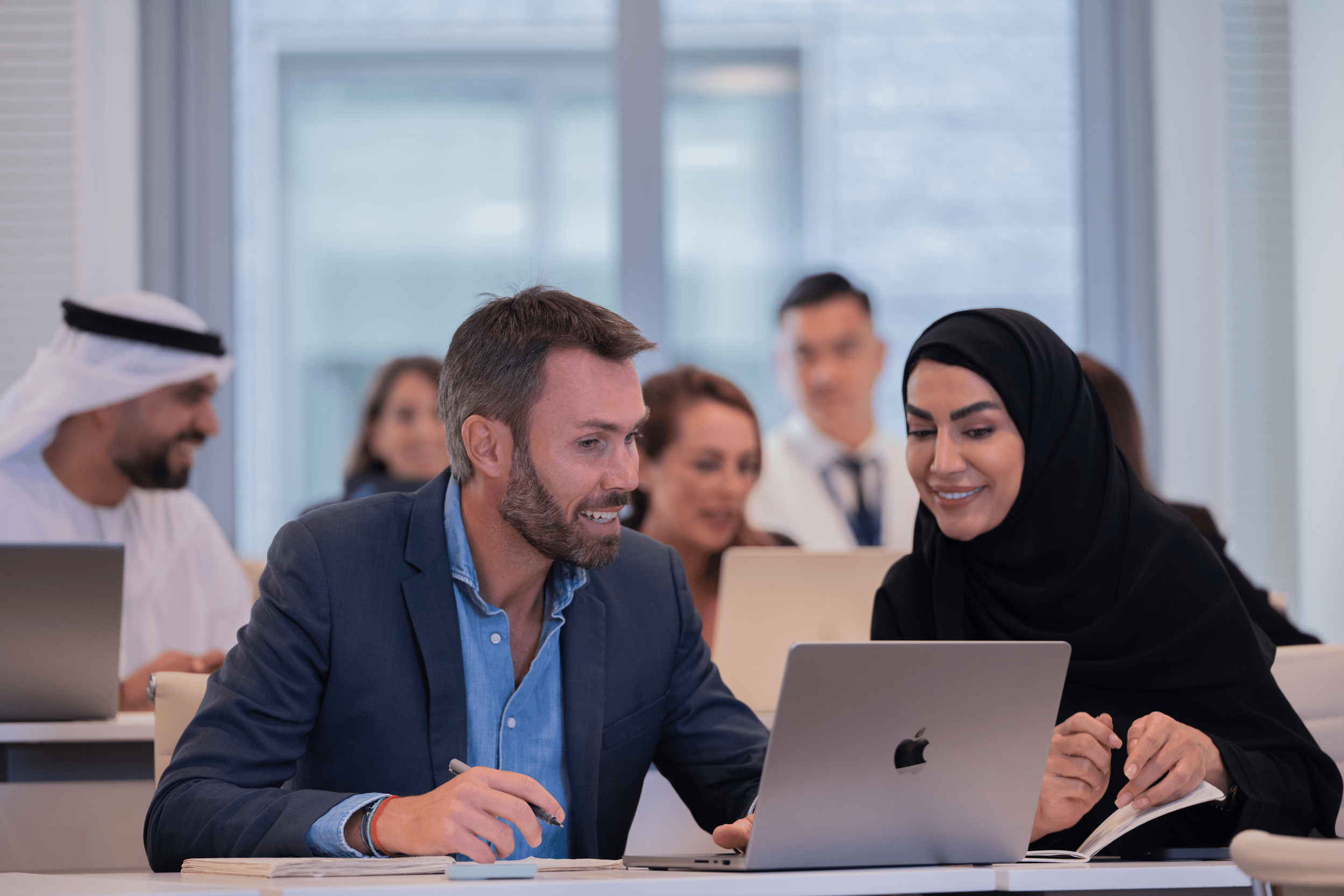 Georgetown Dubai Executive MBA students conversing while looking at a laptop.